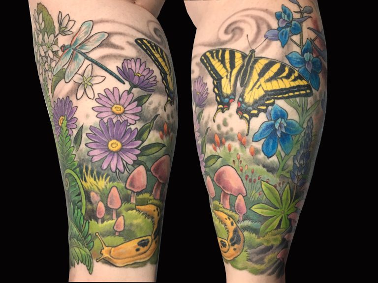 Colorful tattoo on legs featuring flowers, mushrooms, a dragonfly, a yellow butterfly, and a yellow slug amidst green foliage and blue skies.