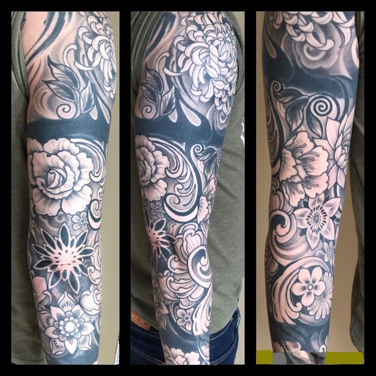 A detailed full sleeve tattoo featuring various floral designs in black and gray ink. The imagery includes flowers, leaves, and intricate patterns. Seen from three different angles on the arm.