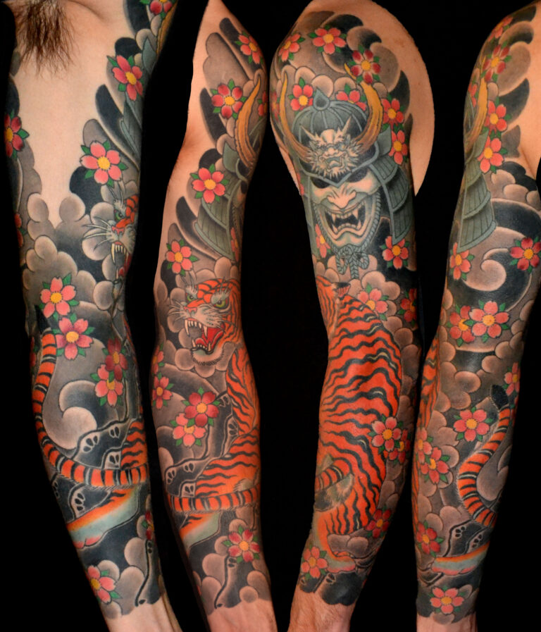 Full sleeve tattoo featuring a traditional Japanese design with a samurai mask, tiger, cherry blossoms, and swirling clouds in bold colors.